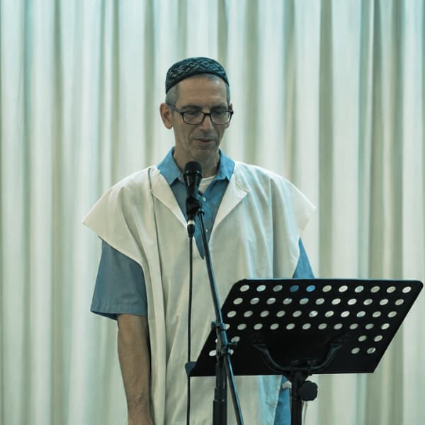 ראובן מודק מקריא טקסט מול סטנד במופע המהפחה הכסידית